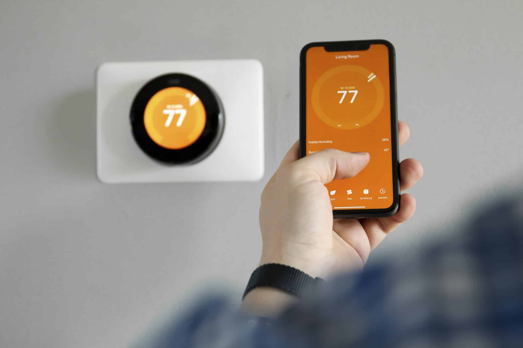 Individual enjoying the ease of using a smart thermostat to adjust temperature and improve energy management.