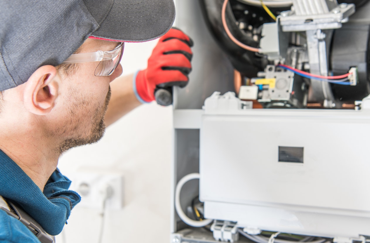 HVAC technician performing central gas heater inspection for efficient fall maintenance and reliable home comfort.